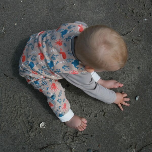 Kind im Strampler am Strand